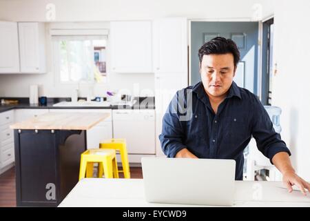 Man typing on laptop at table de cuisine Banque D'Images