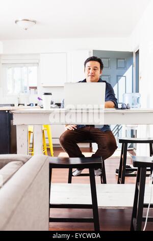 Mature businessman typing on laptop at table de cuisine Banque D'Images