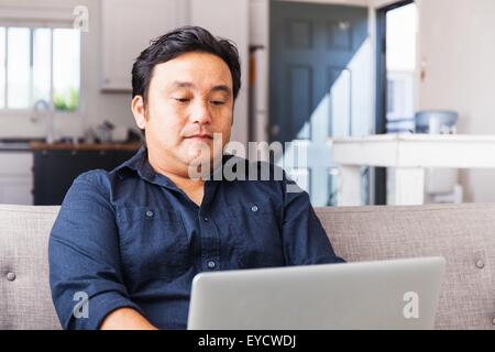 Man working on laptop on sofa Banque D'Images