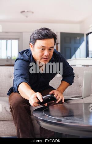 Homme mature sur canapé d'atteindre pour la commande à distance Banque D'Images