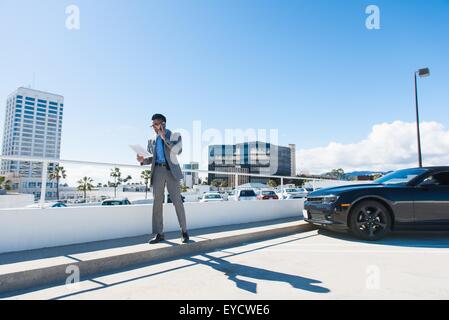 Jeune homme sur le parking sur le toit ville chatting on smartphone Banque D'Images