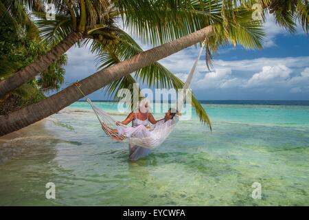 Senior man relaxing in hammock avec femme, Maldives Banque D'Images