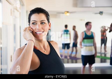 Mid adult woman on cell phone in studio d'exercice Banque D'Images