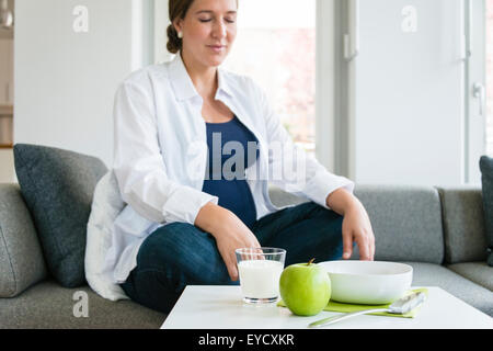 Pregnant woman relaxing in living room Banque D'Images