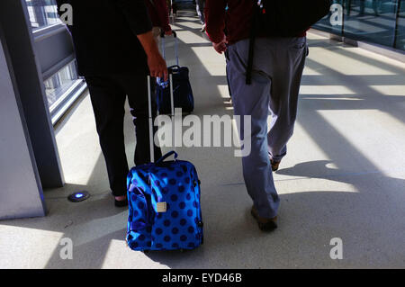 Les passagers tirant leurs valises derrière eux marche à travers l'aéroport de Dublin à Dublin. Banque D'Images