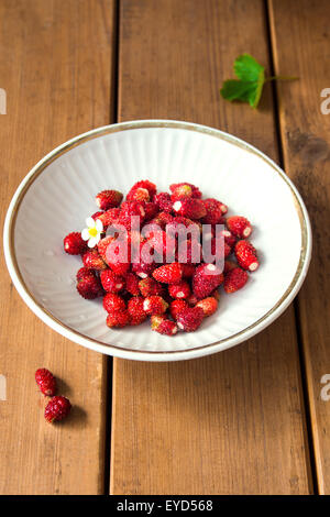 Fraises biologiques sauvages dans un bol blanc sur fond de bois close up Banque D'Images