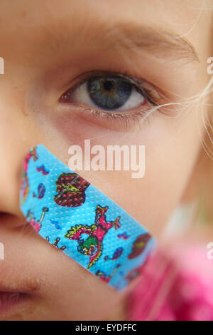 Close up of blessés enfant fille avec le plâtre sur sa joue Banque D'Images