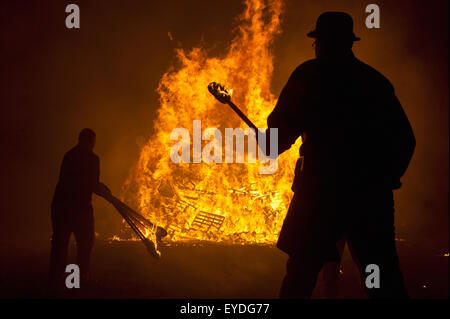 Silhouettes de personnes qui se préparent à lancer des torches brûlant sur Grand Feu à Barcombe Bonfire Night, Barcombe, East Sussex, UK Banque D'Images