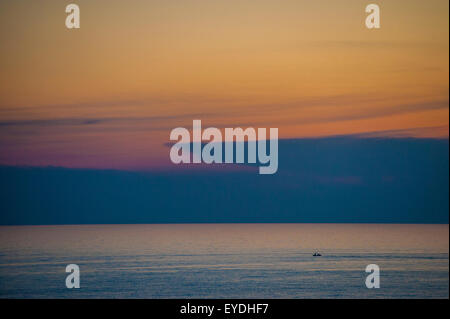 Un seul bateau contre un coucher de soleil spectaculaire à Corfou, Grèce Banque D'Images