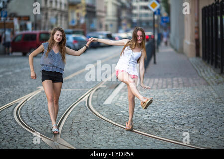 Deux jeunes filles amies à pied le long du tramway et de jouer en soirée, vieille ville. Banque D'Images