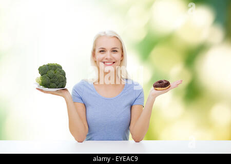 Femme souriante avec brocoli et donut Banque D'Images