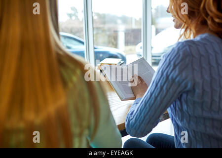 Happy student girls reading book in library Banque D'Images