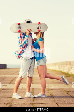 Couple avec skateboard kissing outdoors Banque D'Images