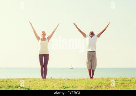 Smiling couple faisant les exercices de yoga en plein air Banque D'Images