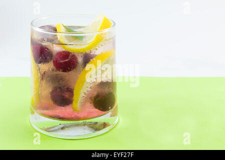 Arôme naturel de fruit cocktail avec de la glace, du citron et des tranches de fruits dans un verre de travers. Boisson froide Banque D'Images