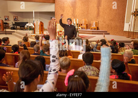 Au couronnement de Marie à une Laguna Niguel, CA, l'église catholique, le monseigneur multiraciale réponses les questions des enfants sur la cérémonie. Pensée de mai à la Vierge Marie sont un rituel catholique romaine traditionnelle et l'honorer comme "la Reine de mai." Remarque statue en arrière-plan. Banque D'Images