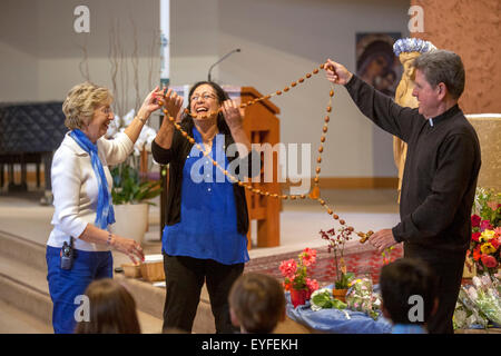 Au couronnement de Marie à une Laguna Niguel, CA, l'église catholique, l'évêque et ses bénévoles afficher un chapelet géant tout en répondant aux questions des enfants sur la cérémonie. Pensée de mai à la Vierge Marie sont un rituel catholique romaine traditionnelle et l'honorer comme "la Reine de mai." Remarque statue en arrière-plan. Banque D'Images