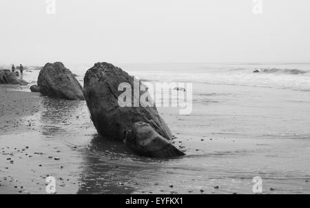 Rochers sur la plage à marée basse, en noir et blanc. Banque D'Images