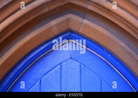 Sommet d'une porte d'église bleue dans un cadre voûté en grès Banque D'Images