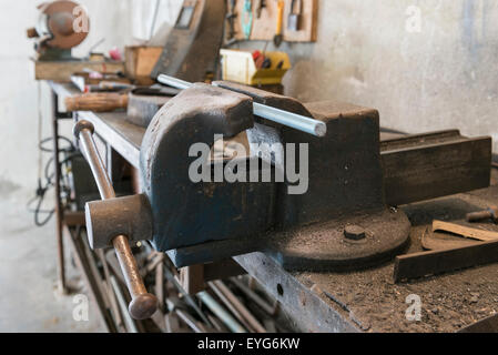 Vieux banc vice avec filet de bar et de vieux outils de travail dans un garage accueil Banque D'Images