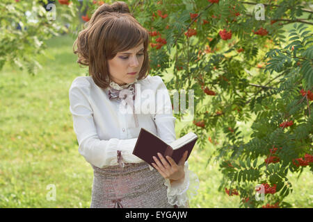 Belle fille trouvé quelque chose d'intéressant dans le livre pendant la lecture en plein air Banque D'Images