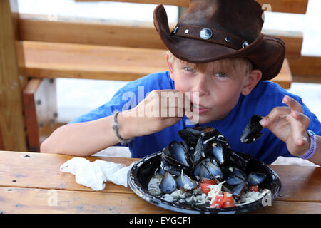 Saint Petersburg, Floride, garçon avec chapeau de cowboy de manger des moules fraîches Banque D'Images