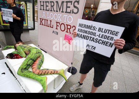 Berlin, Allemagne. 29 juillet, 2015. Les membres du groupe de défense des droits des animaux Peta manifestation devant un magasin de la marque Hermes contre l'assassinat de crocodiles pour les sacs en cuir de luxe à Berlin, Allemagne, 29 juillet 2015. Un modèle, peint avec de la peau de crocodile artificiel, se trouve dans un faux mare de sang sur le Kurfürstendamm à Berlin. Dpa : Crédit photo alliance/Alamy Live News Banque D'Images