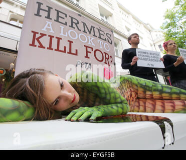 Berlin, Allemagne. 29 juillet, 2015. Les membres du groupe de défense des droits des animaux Peta manifestation devant un magasin de la marque Hermes contre l'assassinat de crocodiles pour les sacs en cuir de luxe à Berlin, Allemagne, 29 juillet 2015. Un modèle, peint avec de la peau de crocodile artificiel, se trouve dans un faux mare de sang sur le Kurfürstendamm à Berlin. Dpa : Crédit photo alliance/Alamy Live News Banque D'Images