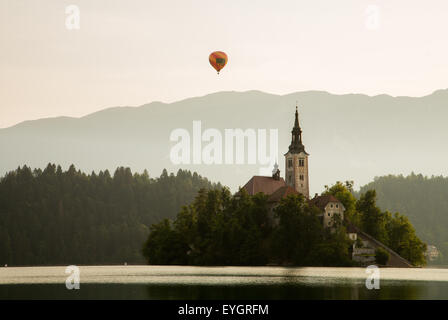 Un ballon à air chaud s'élève au-dessus de la montagne derrière le lac de Bled, Slovénie l'église de l'île. Banque D'Images