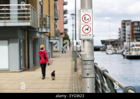 Une fonction pas 'Dog Messing' et 'Dogs sur le plomb' signe sur un lampadaire en ville, un chien walker avec un chien en laisse vient tout juste d'adopter le signe Banque D'Images