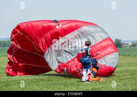 Parachutiste avec parachute rouge après l'atterrissage sur le terrain. Banque D'Images