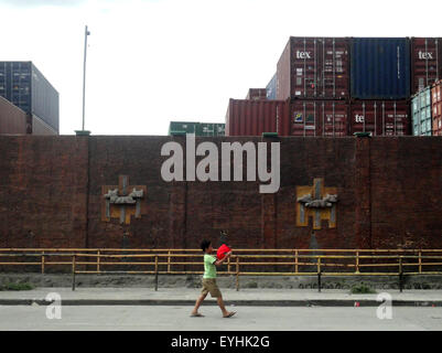 Malabon City, Philippines. 30 juillet, 2015. Un enfant philippin passe devant un conteneur d'expédition garage appartenant à une entreprise de camionnage en Malabon City. © Richard James Mendoza/Pacific Press/Alamy Live News Banque D'Images