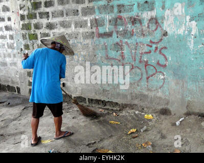 Navotas City, Philippines. 30 juillet, 2015. Un Philippin les socs à côté d'un graffiti à la gloire d'un groupe appelé les insurrectionnels armés Alex Boncayao Brigade (ABB) à Malabon City. © Richard James Mendoza/Pacific Press/Alamy Live News Banque D'Images