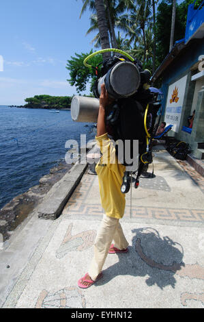 Une femme porter porte deux réservoirs de plongée entièrement chargé sur sa tête, Tulamben, Bali, Indonésie (pas de M.) Banque D'Images