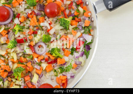 Salade de légumes sur une casserole prêts à être cuisinés pour un repas santé mis sur la table en bois blanc Banque D'Images