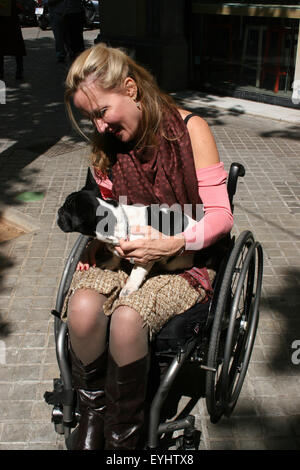 Femme dans un fauteuil roulant avec un petit chien sur ses genoux Banque D'Images