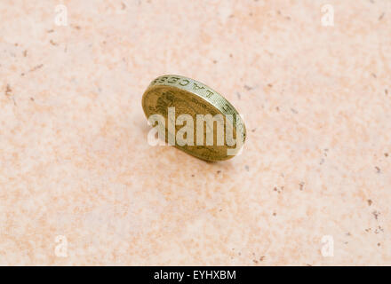 Seul British pound coin debout sur le bord sur le plancher Banque D'Images