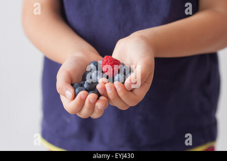 Enfant, tenant les framboises et les bleuets dans ses mains, isolated on white Banque D'Images