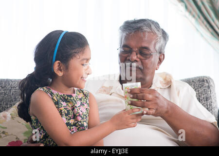 Portrait de famille indienne à la maison. Petit-enfant donnant un verre d'eau pour un grand-parent . Style de vie des gens d'Asie. Un grand-père Banque D'Images