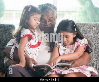 Grand-père asiatique et petites-filles lecture livre d'histoires. Heureux famille indienne à la maison. Les grands-parents et petits-enfants des natures mortes à l'intérieur Banque D'Images