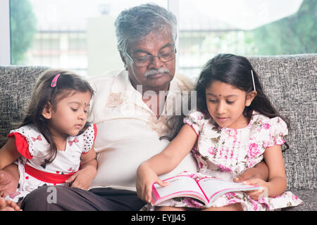 Les grands-parents et petits-enfants la lecture de livre d'histoires. Heureux famille indienne à la maison. Grand-père asiatique et petites-filles de la vie intérieure Banque D'Images