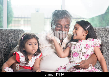 Les grands-parents et petits-enfants histoire lecture livre ensemble. Heureux famille indienne à la maison. Grand-père asiatique et petites-filles ind Banque D'Images
