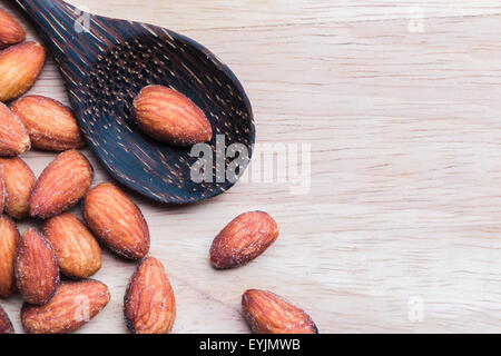 Amandes en cuillère en bois sur fond de bois. Banque D'Images