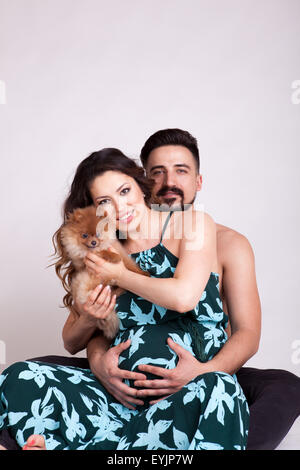 Femme enceinte avec chiot dans les mains et tenant son mari par derrière. Tournage Studio Banque D'Images