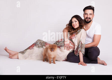 Femme enceinte avec l'heureux mari et chien dans studio tournage étendu sur le plancher de studio Banque D'Images