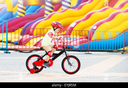 Joyeux petit garçon à cheval sur la bicyclette en amusement park, heureux de l'enfance insouciante, s'amuser en plein air en summer camp Banque D'Images