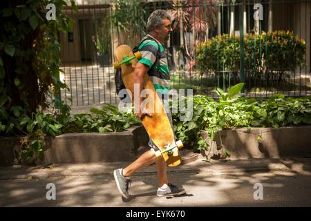 Homme mûr se promener sur un trottoir l'exercice de la planche à roulettes, de Rio de Janeiro, Brésil Banque D'Images