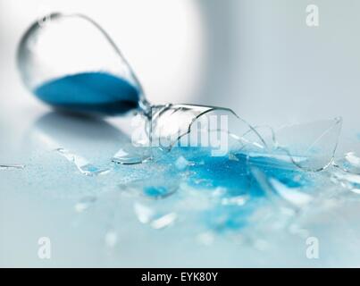 Sablier de verre cassée avec sable bleu coule Banque D'Images