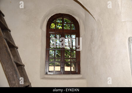 Vieille fenêtre avec grille en fer sur le mur du bâtiment médiéval avec échelle en bois à côté d'elle Banque D'Images