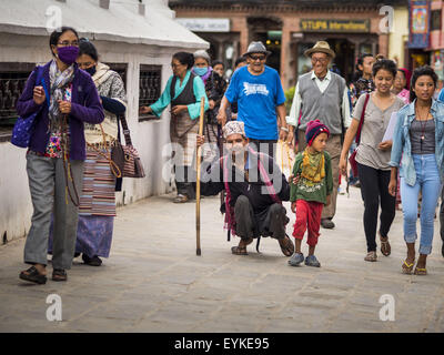 Katmandou, Népal. 31 juillet, 2015. Un homme et son fils inscrivez-vous d'autres bouddhistes dans le traitement autour de Bodhnath Stupa. Bodhnath Stupa dans le Bouda article de Katmandou est l'un des instruments les plus anciens et les stupas bouddhistes au Népal. La région est devenue le centre de la communauté des réfugiés tibétains à Katmandou. Sur les nuits de pleine lune des milliers de bouddhistes tibétains et népalais viennent à la stupa et participer dans les processions autour de la stupa. Le stupa a été lourdement endommagée par le séisme du 25 avril 2015 et les gens ne sont plus autorisés à monter sur le stupa, maintenant ils marchent autour de la base et de prier avec Banque D'Images